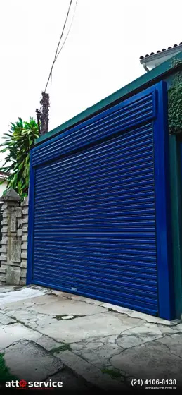 Porta de enrolar azul em garagem com jardim