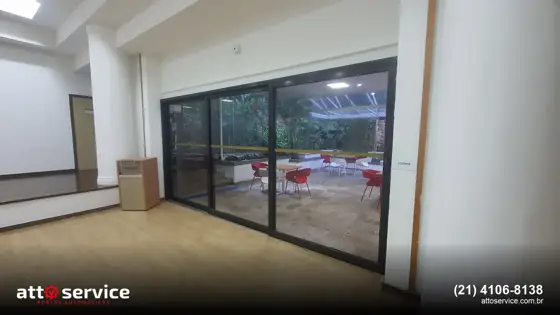 Porta de vidro deslizante com perfil preto em salão amplo
