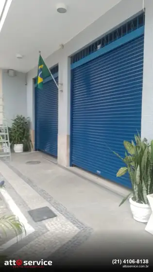 Entrada de prédio com bandeira: porta social azul junto à porta principal