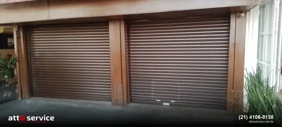 Garagem com pilar de madeira separando porta social e porta principal marrons